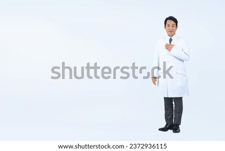 Standing middle aged Asian doctor. Royalty-Free Stock Photo #2372936115