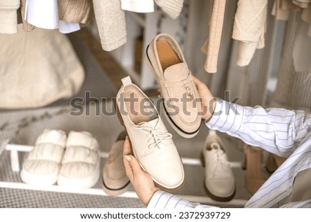 Modern woman choosing shoes putting on rack wardrobe comfortable storage organizing top view. Female arrangement stylish beige neutral fashion footwear domestic space organize tidying up maintaining Royalty-Free Stock Photo #2372939729