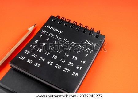 January 2024 desk calendar with pencil on orange color background. Royalty-Free Stock Photo #2372943277