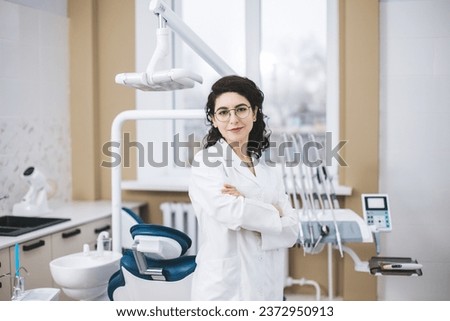 Professional young dentist posing beside modern equipment in a dental clinic. Royalty-Free Stock Photo #2372950913