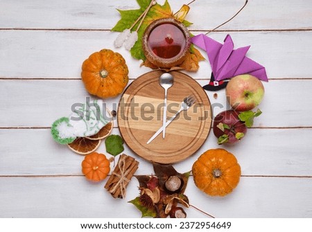 Autumn background with mini pumpkins, cup of tea, spices and apples with space for text on a light wooden background. Autumn time, design.