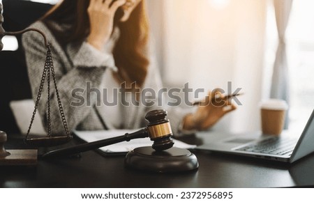 justice and law concept.law theme  wooden desk, books, balance. Male judge in a courtroom the gavel,working with digital tablet computer on desk