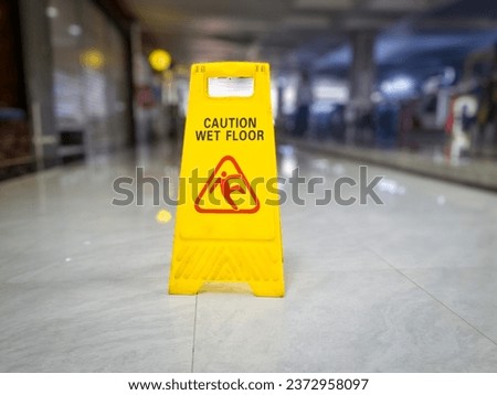 yellow signs that say wet floors or slippery floors in mall hallways and public spaces Royalty-Free Stock Photo #2372958097