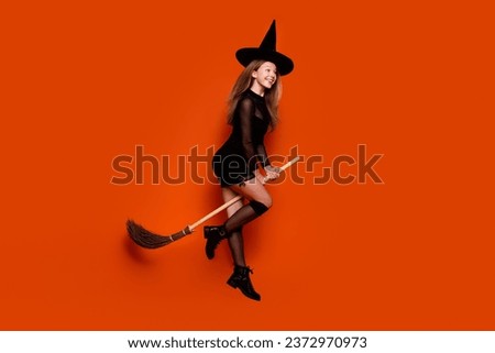 Full body photo of attractive blonde teen woman broom flying sabbath dressed black halloween clothes isolated on orange color background