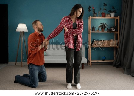 Funny traitor husband on floor imploring his wife to give second chance. Relationship breakup and divorce concept Royalty-Free Stock Photo #2372975197