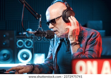 Professional radio host wearing headphones and talking into the microphone: radio and communication concept