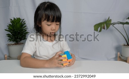 Asian little cute girl holding Rubik's cube in her hands. Rubik's cube is a game that increases the intelligence of children Royalty-Free Stock Photo #2372992049