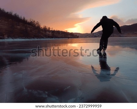 Silhouette of a man on the ice of Lake Baikal in the rays of sunset