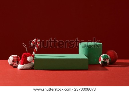Abstract background for branding and minimal presentation with Xmas concept. Cute candy canes, woolen hat and baubles decorated with green podiums on red background