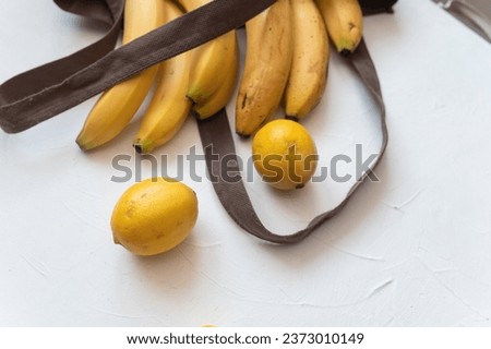 Sweet Ripe yellow bananas in shopping bag on table white background. Healthy tropical food.
