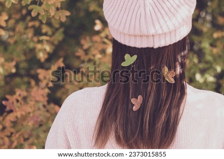 Unrecognizable woman with autumn, fall leaves in her dark hair, selective focus, stock photo