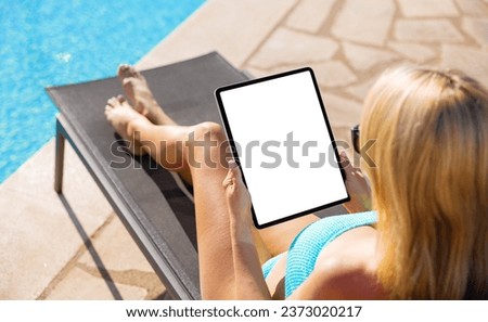 Woman holding tablet computer vertically by the pool, view from above