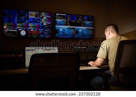 TV engineer at editor in studio. TV editor working with vision mixer in a television broadcast gallery.Man sat at a vision mixing panel in a television studio gallery Royalty-Free Stock Photo #237302128