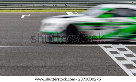Race car blurred motion crossing the finish line on international circuit speed track, Motion blur Racing car crossing finish line on asphalt race track.