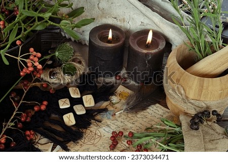 Runes, black candles and old manuscript on altar table. Occult, esoteric and divination still life. Mystic Halloween background with vintage objects for magic ritual