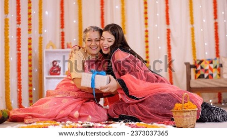 An affectionate Indian mother giving a Diwali gift to her young daughter - Diwali celebrations. Mother and daughter bonding with each other during Diwali festival - an auspicious occasion, a family...
