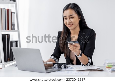 Young Asian woman orders goods online using a laptop and a credit card. Online shopping, delivery and payment systems concept.
