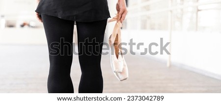 ballet dancer holding pointe shoes in the studio
