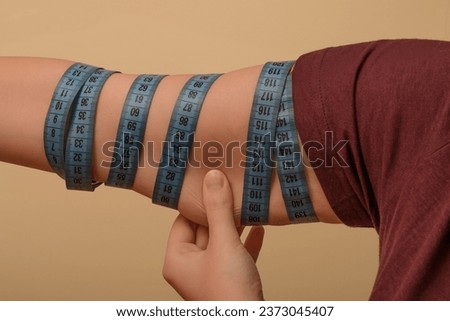 Woman measures arm circumference, lack of muscles and sagging skin Royalty-Free Stock Photo #2373045407