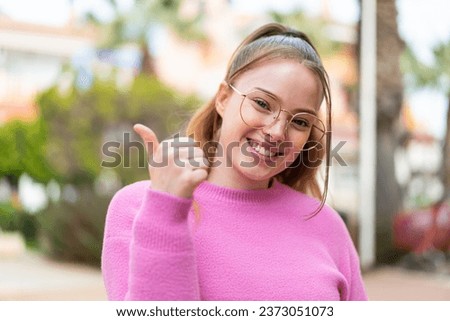Young pretty girl at outdoors With glasses and with thumb up