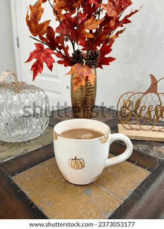 A hot cup of coffee sitting on a table filled with Autumn decorations.