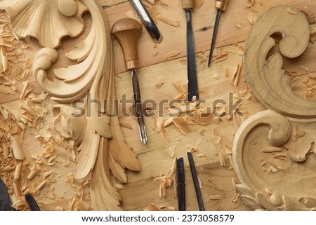 Hands of craftsman carve with a gouge in the hands on the workbench in carpentry. Wood carving tools close-up top view. Royalty-Free Stock Photo #2373058579