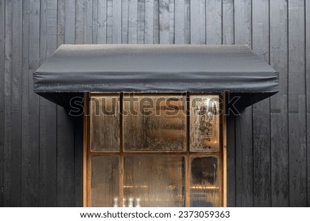 black awning canvas over the shop windows on the black wooden wall.