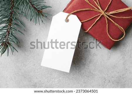 White blank paper tag or label with christmas gift box and fir tree branch, top view, copy space
