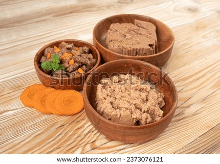 Pet Food on Wooden Floor Background, Wet Food for Cats in Wood Bowl with Carrots, Dog Canned Pate, Soft Pet Food on White Background Royalty-Free Stock Photo #2373076121