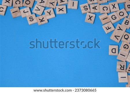 Bunch of letters on wooden tiles isolated on blue background with space for copy text or quote or some other kind of ads