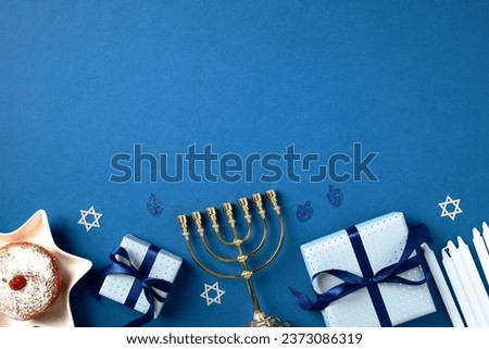 Jewish holiday Hanukkah concept. Flat lay gold menorah, traditional jelly donut, gift boxes, candles, confetti on blue background.