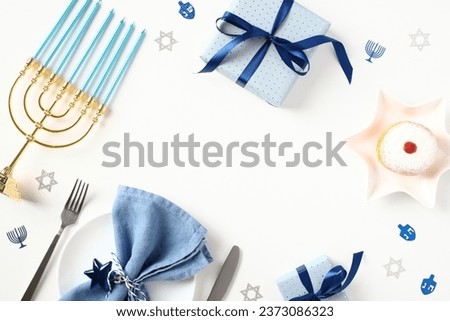 Concept of jewish holiday Hanukkah top view. Frame border of menorah with blue candles, gift boxes, tableware with cutlery, donut, confetti on white background. Royalty-Free Stock Photo #2373086323