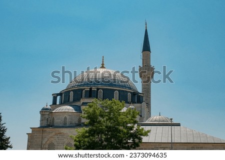 The graceful contours of a traditional Turkish mosque softly contrast the clear blue sky, surrounded by a serene ambiance.