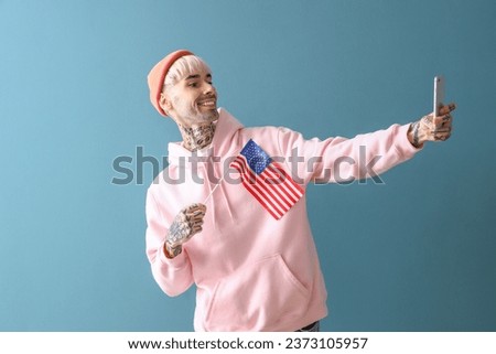 Young man with USA flag taking selfie on blue background