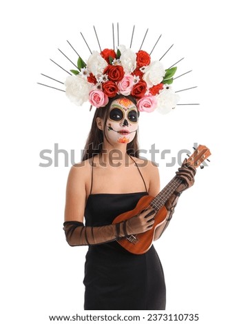 Young woman with painted skull playing guitar on white background. Mexico's Day of the Dead (El Dia de Muertos) celebration