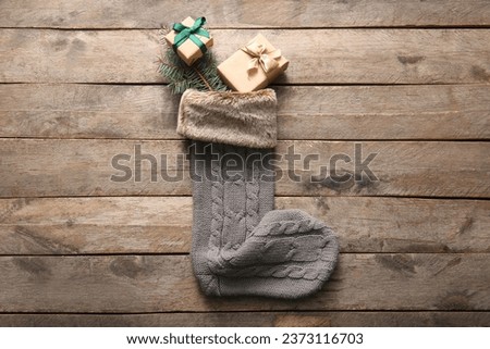 Beautiful Christmas sock with gift boxes and fir branch on wooden background