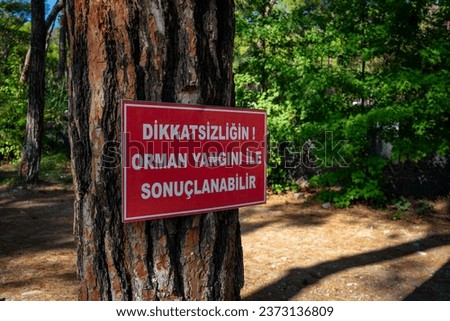 Turkish forest fire warning sign on tree at the forest, close up and green scenery and summertime