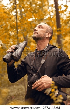 Man using binoculars and camera for birdwatching and other observing animals in nature. Royalty-Free Stock Photo #2373143281