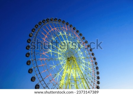 High neon ferris wheel at nighttime in an amusement park Navruz or Anhor in Tashkent, Uzbekistan.