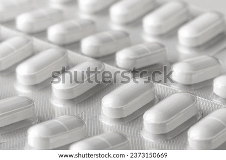 White pills in blister pack with selective focus and unfocused white background prepared for copy space. White pills on white background for wallpaper. Concept of pill and medications Royalty-Free Stock Photo #2373150669