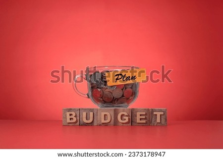 Budget allocation and plan concept. The word BUDGET and a glass cup filled with coins at the back with message on "Plan". Copy space for text and messages