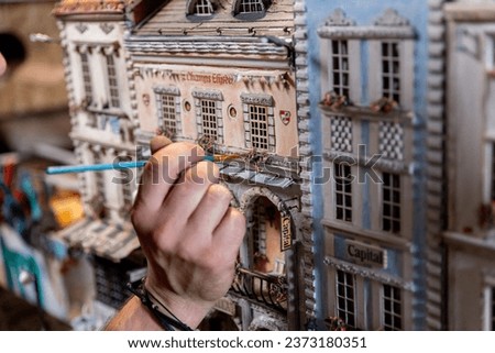 Modeller man working at scale model of miniature building in his workshop full of tools Royalty-Free Stock Photo #2373180351