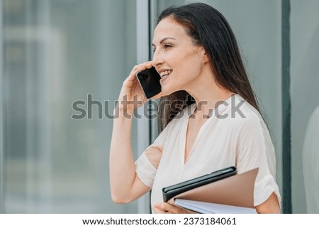 business woman with mobile phone and documents on the street