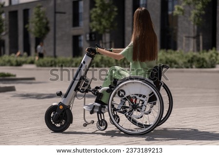 A woman in a wheelchair with an assistive device for manual control. Electric handbike.  Royalty-Free Stock Photo #2373189213