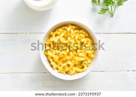Macaroni and cheese in bowl over wooden background. Top view, flat lay Royalty-Free Stock Photo #2373195937