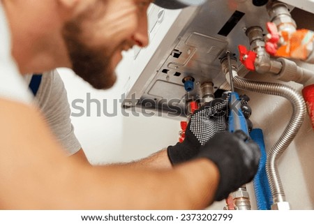 Closeup of plumber using screwdriver while installing new steel hot water central heating system in apartment Royalty-Free Stock Photo #2373202799