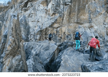 Climbers preparing for ascent. Three male female persons walking on the rocks. Extreme outdoor sport.
