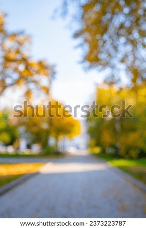 Blurred background of park in fall season. Bright autumn trees with falling yellow leaves in the park. Beautiful sunny autumn day. Autumn landscape in the city Royalty-Free Stock Photo #2373223787