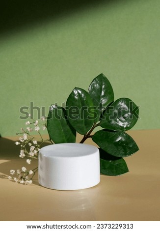 Minimal mock up cosmetic product with flowers and green leaves, green and yellow background with copy space 