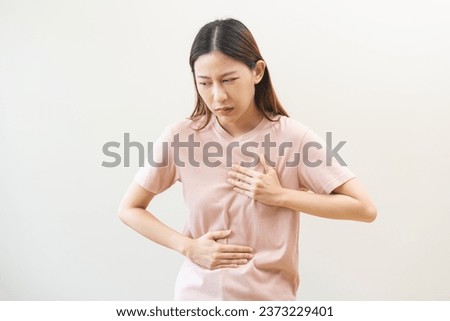 Acid reflux disease, suffer asian young woman have symptom gastroesophageal, esophageal, stomach ache and heartburn pain hand on chest from digestion problem after eat food, Healthcare medical concept Royalty-Free Stock Photo #2373229401